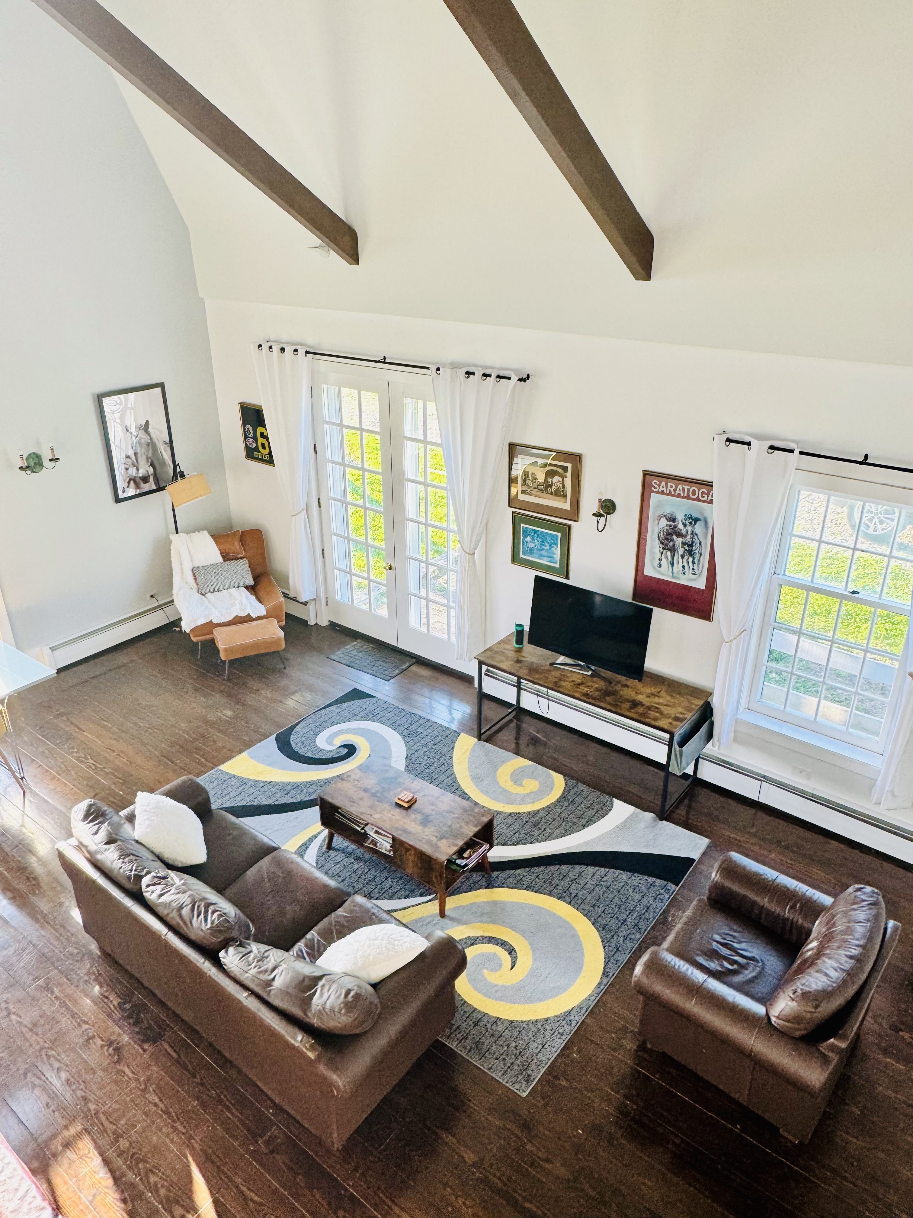 Open-plan living room with leather sofas beneath cathedral beams