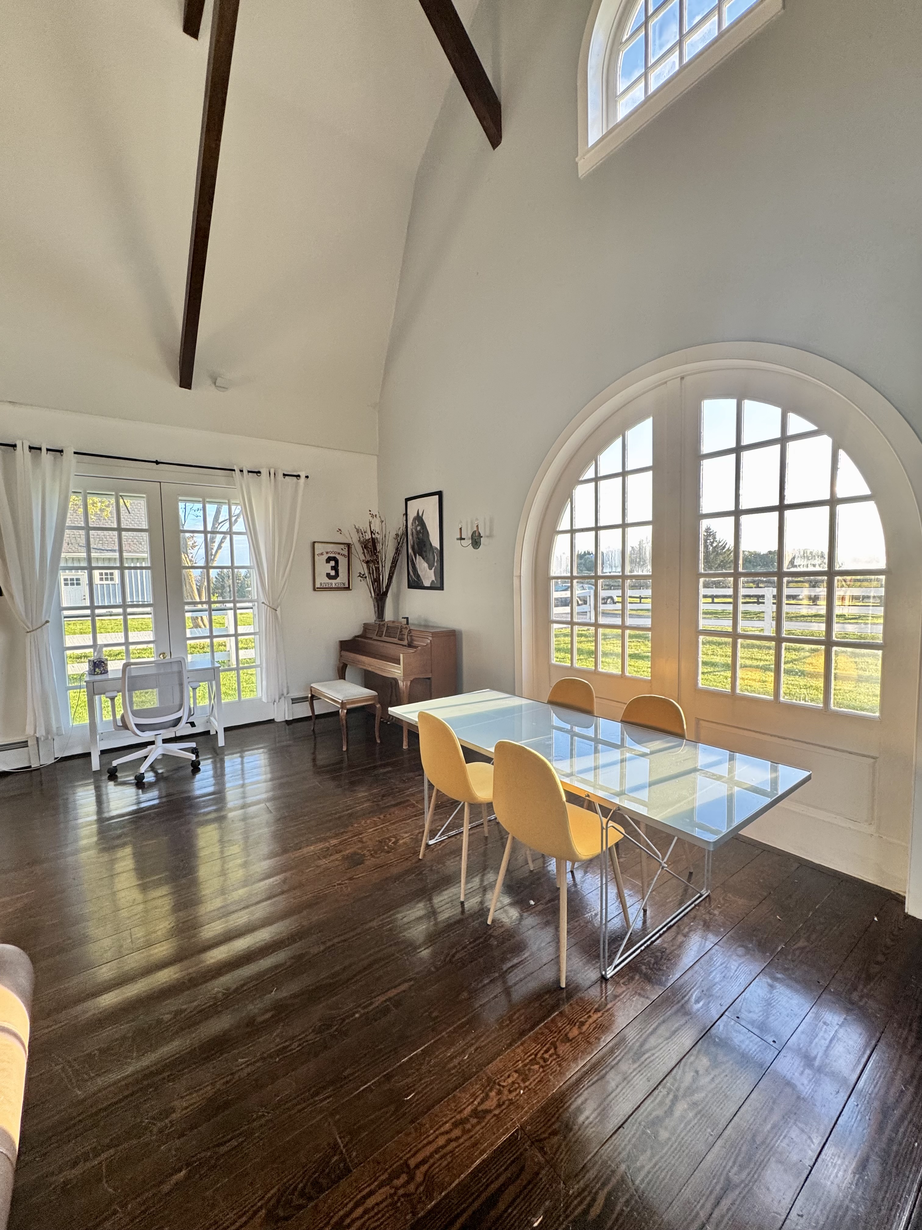 Glass dining table framed by a soaring arched window