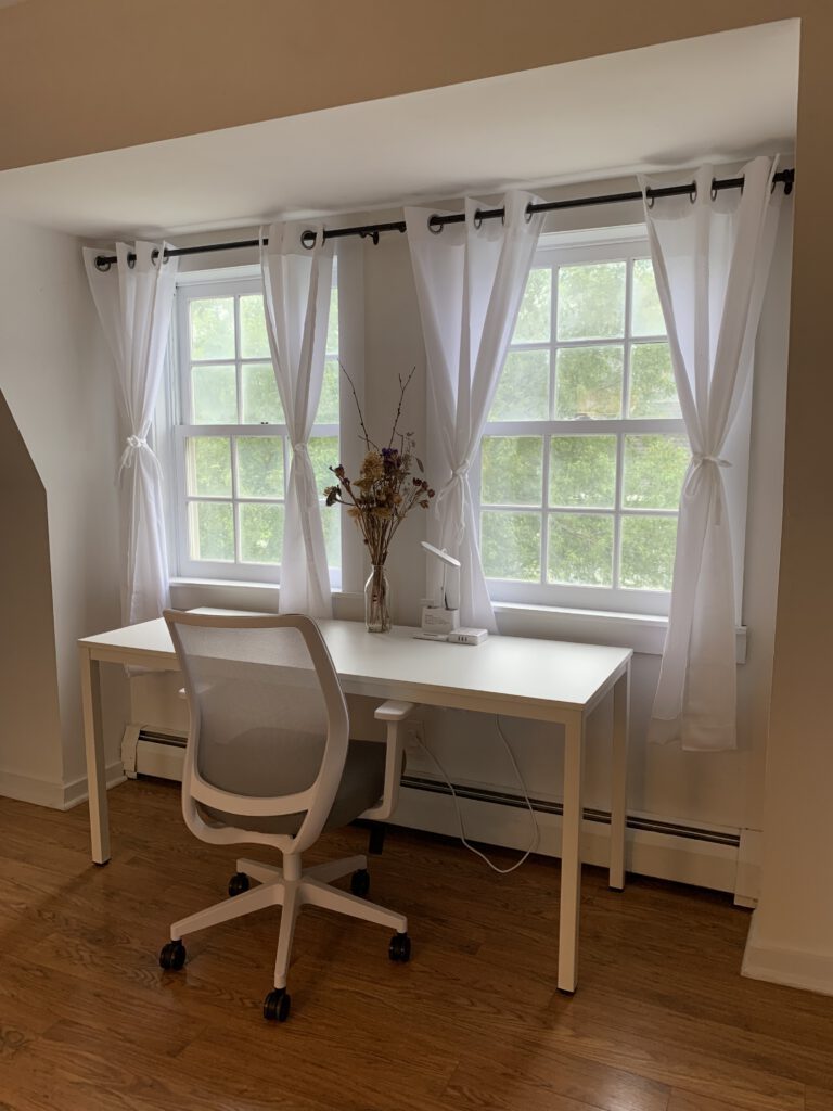Dedicated workspace beside curtained farm-view windows